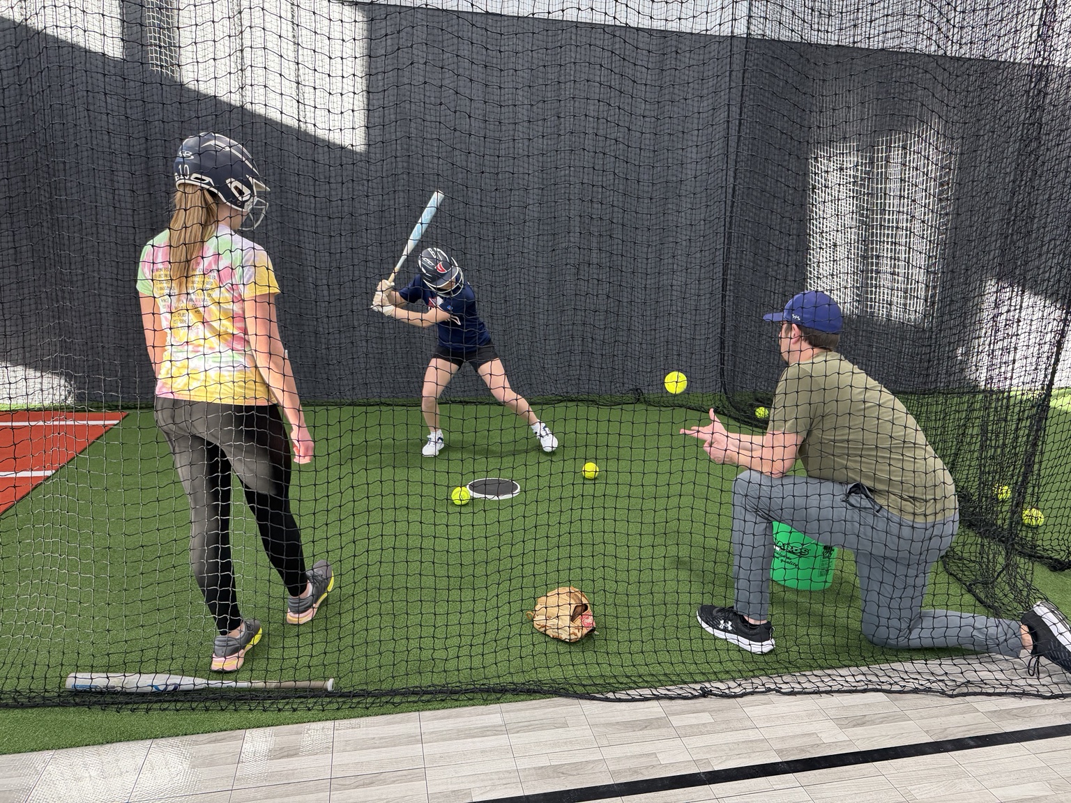 Softball player practicing inside an indoor batting cage