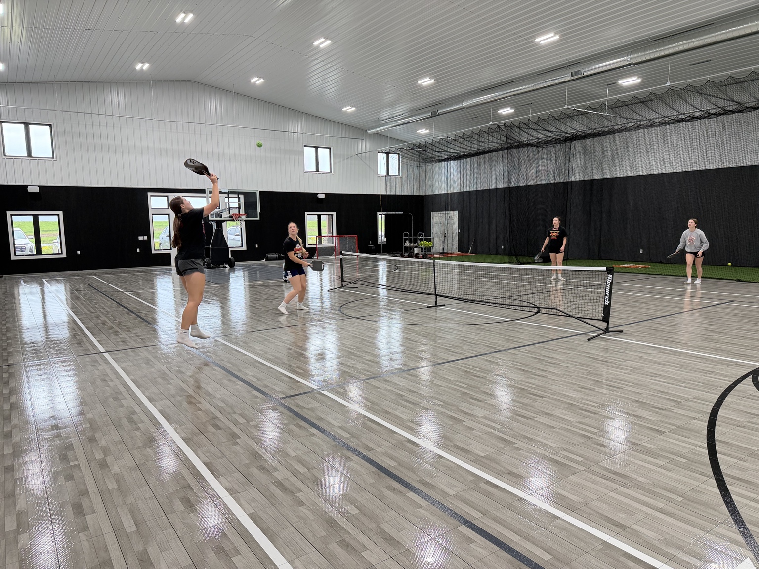 Family playing pickleball across the full indoor court